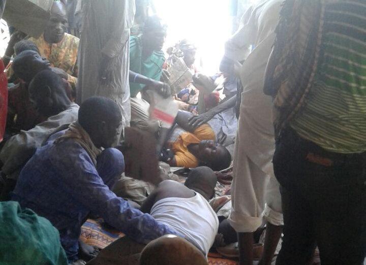 Injured people are comforted at the site after a bombing attack of an internally displaced persons camp in Rann