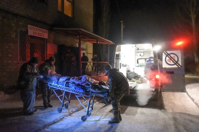 Українські військові медики несуть пораненого в машину швидкої допомоги