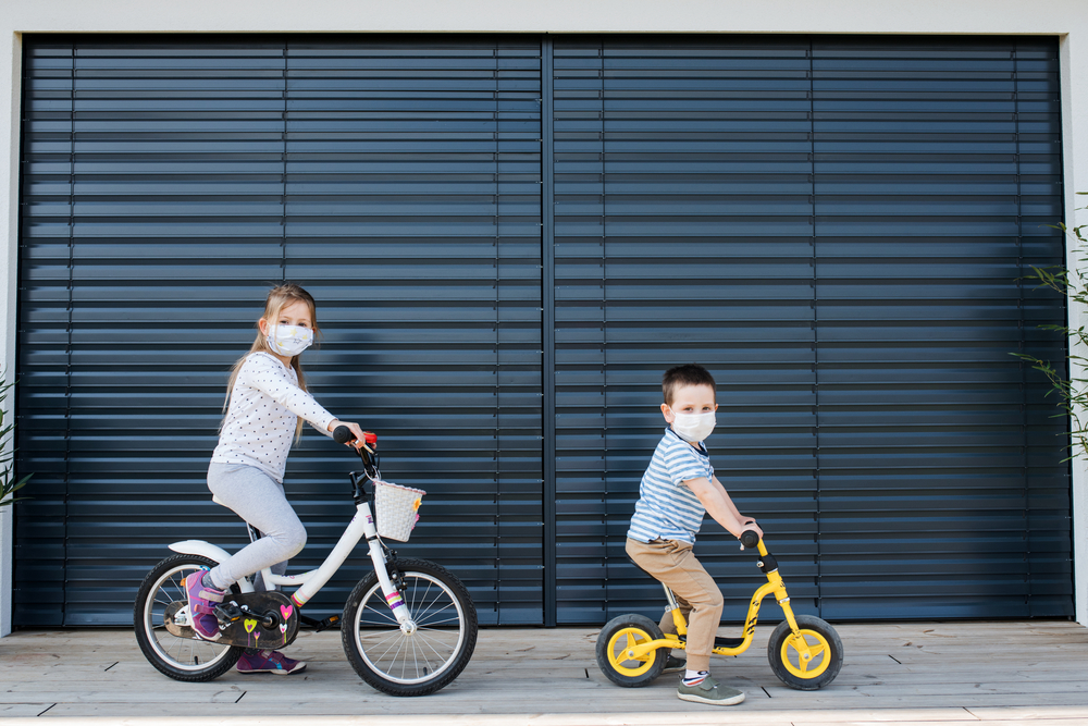 Small girl and boy with bicycles outdoors at home. Corona virus and quarantine concept.