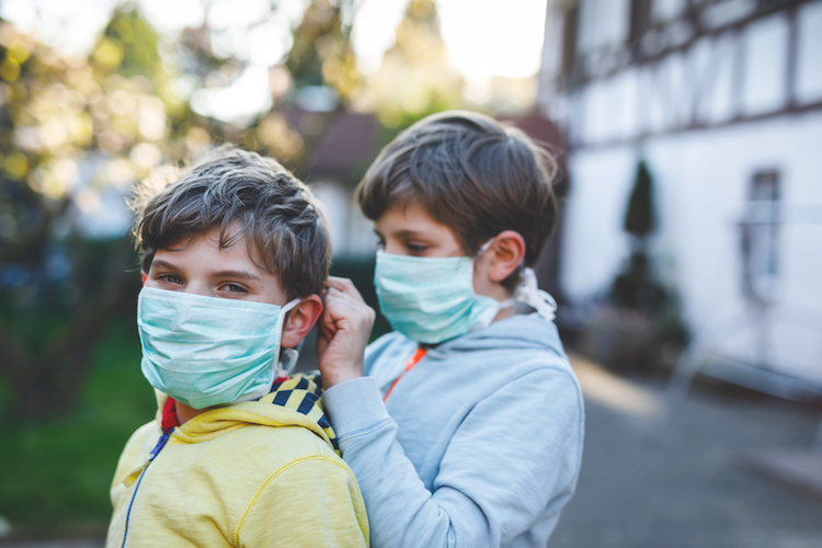Two kids boys in medical mask as protection against pandemic coronavirus disease. Children, lovely siblings and best friends using protective equipment as fight against covid 19.