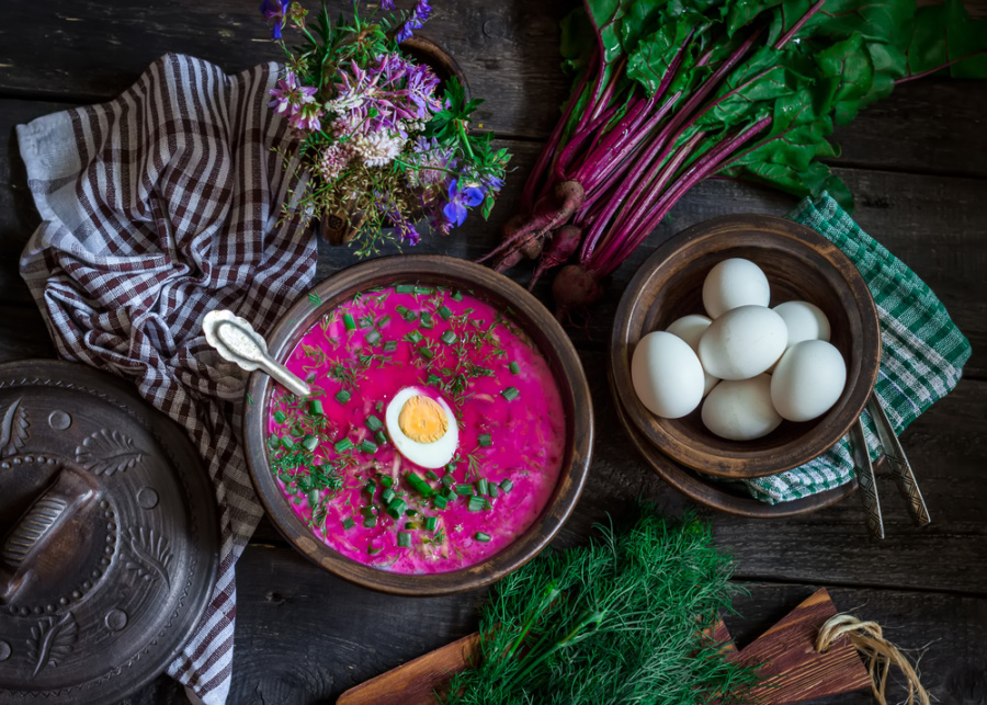 Russian cold soup with beetroot, bowl,spoons,greenery on dark wooden table. Style rustic.