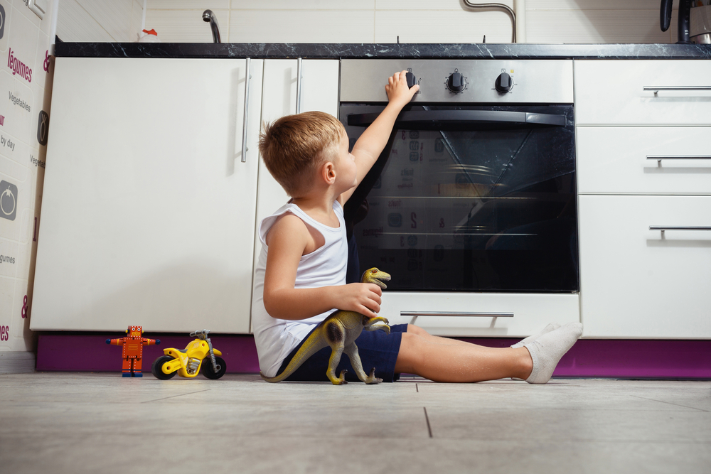 child playing in the kitchen with a gas stove.
