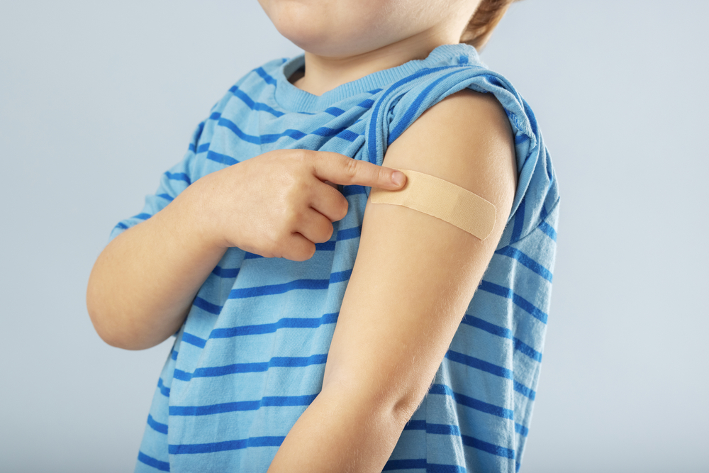 Хлопчик показує на пластир після вакцинації