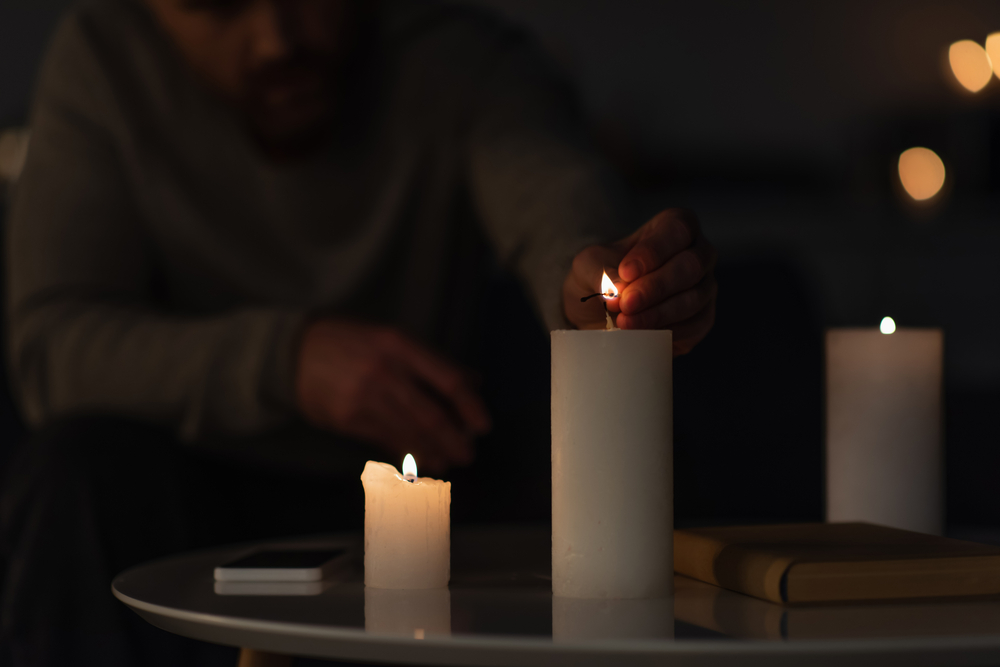 чоловік запалює свічки на столі