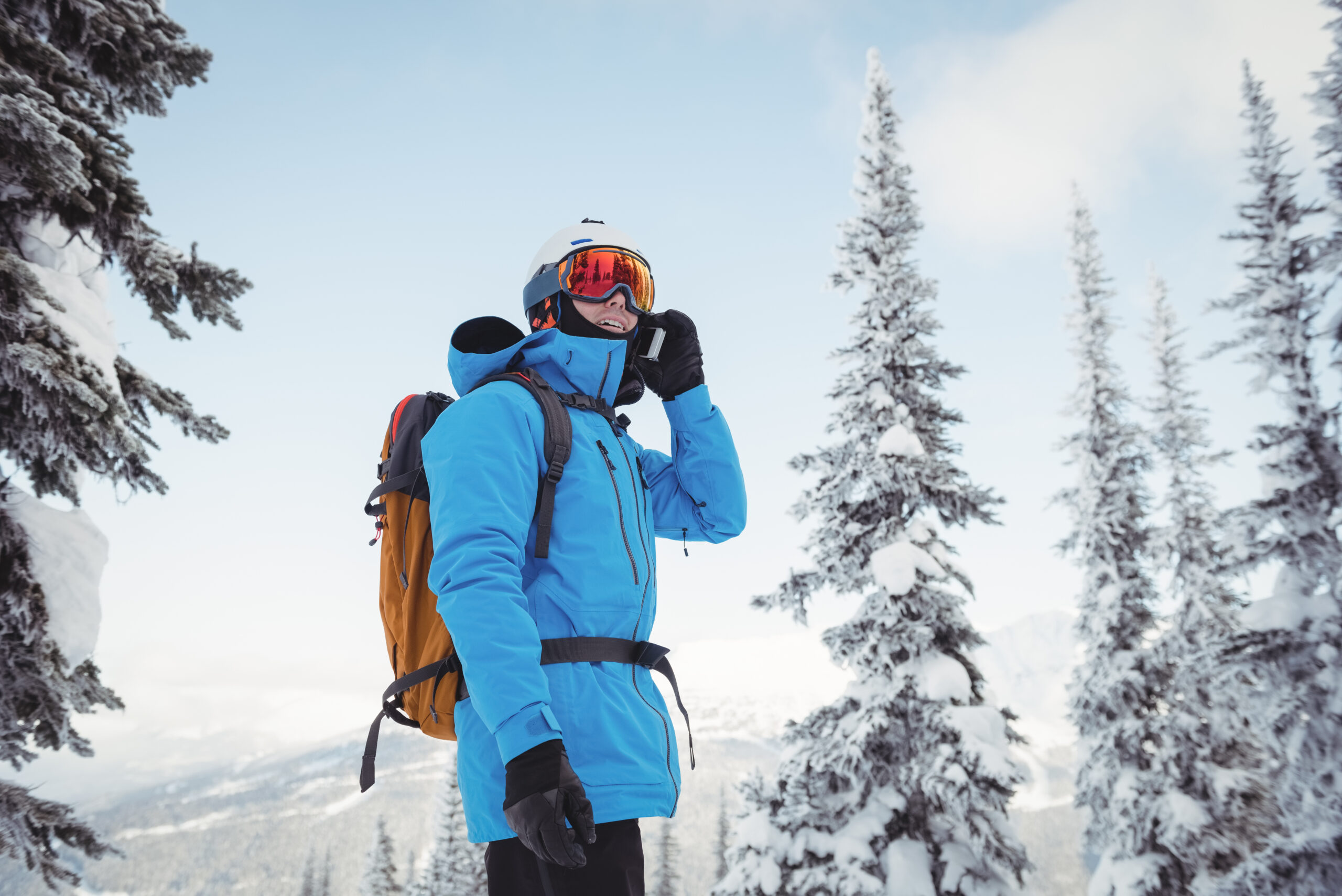 Skier talking on mobile phone on snow covered landscape