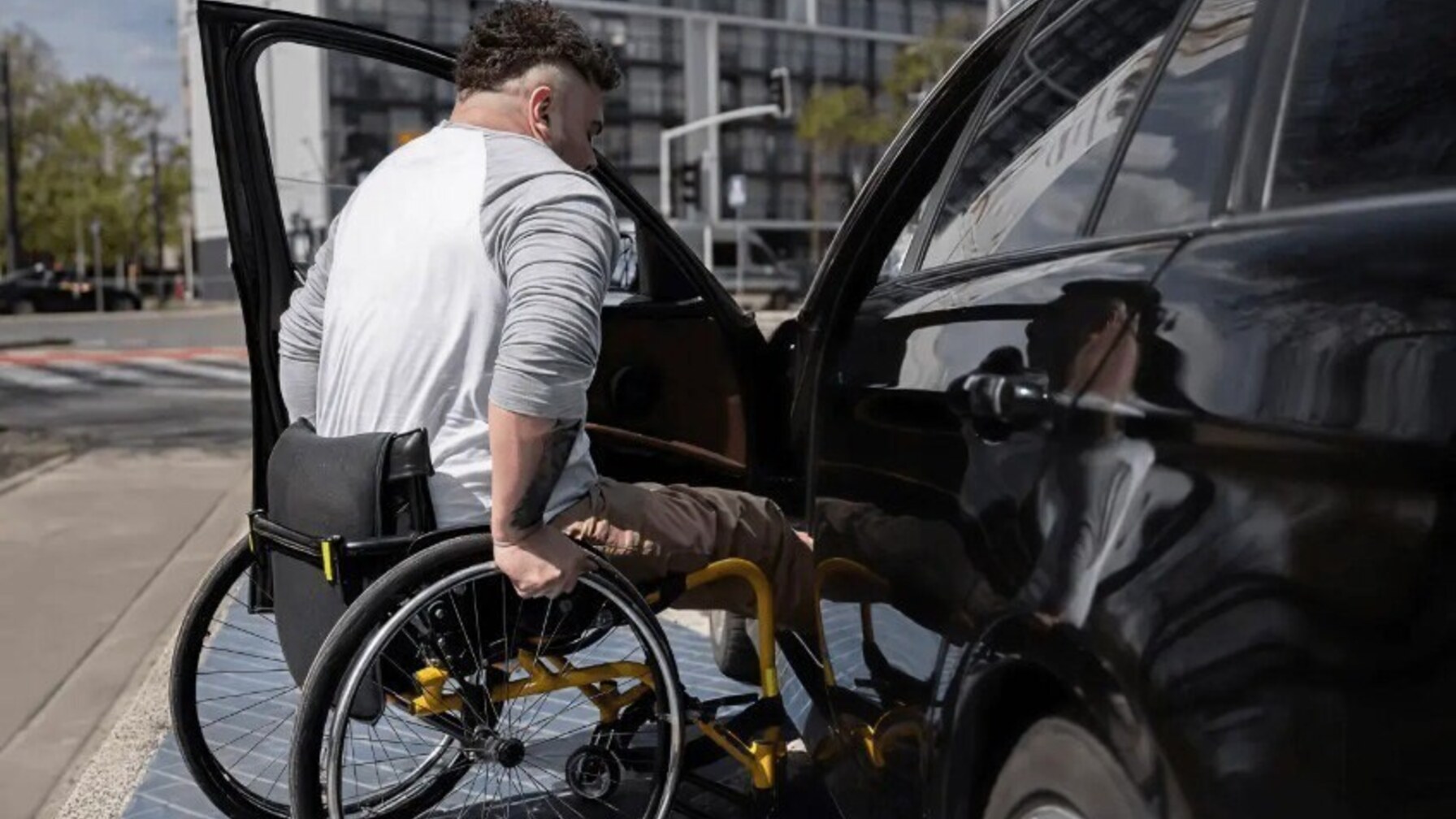 чоловік на колісному кріслі сідає в авто