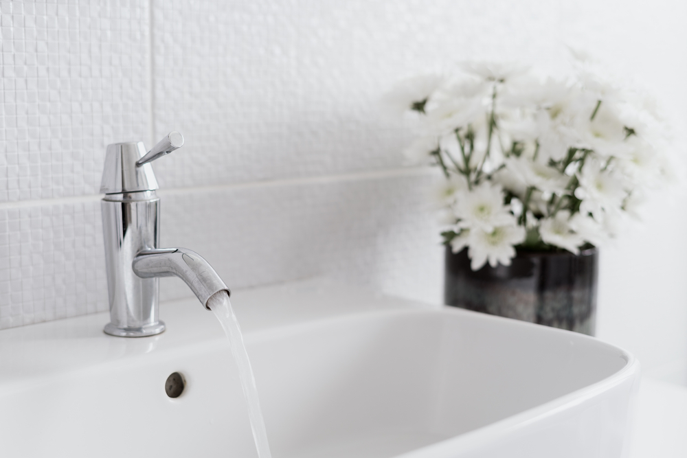 White sink with flowing water in bathroom interior design